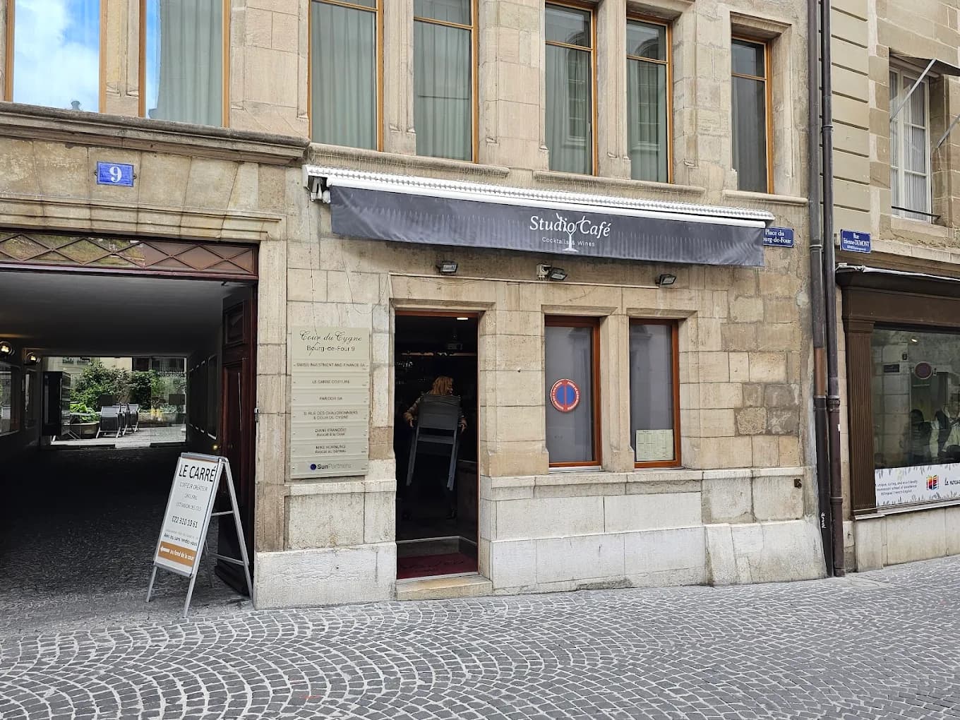 Devanture du Studio Café, store sombre et entrée en pierre, Place du Bourg-de-Four à Genève